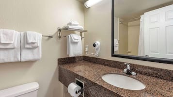 A bathroom with a granite countertop, white sink, and a towel rack with folded towels.