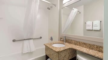 Un baño con lavamanos de granito, un espejo, ducha con puerta de vidrio y un perchero para toallas.
