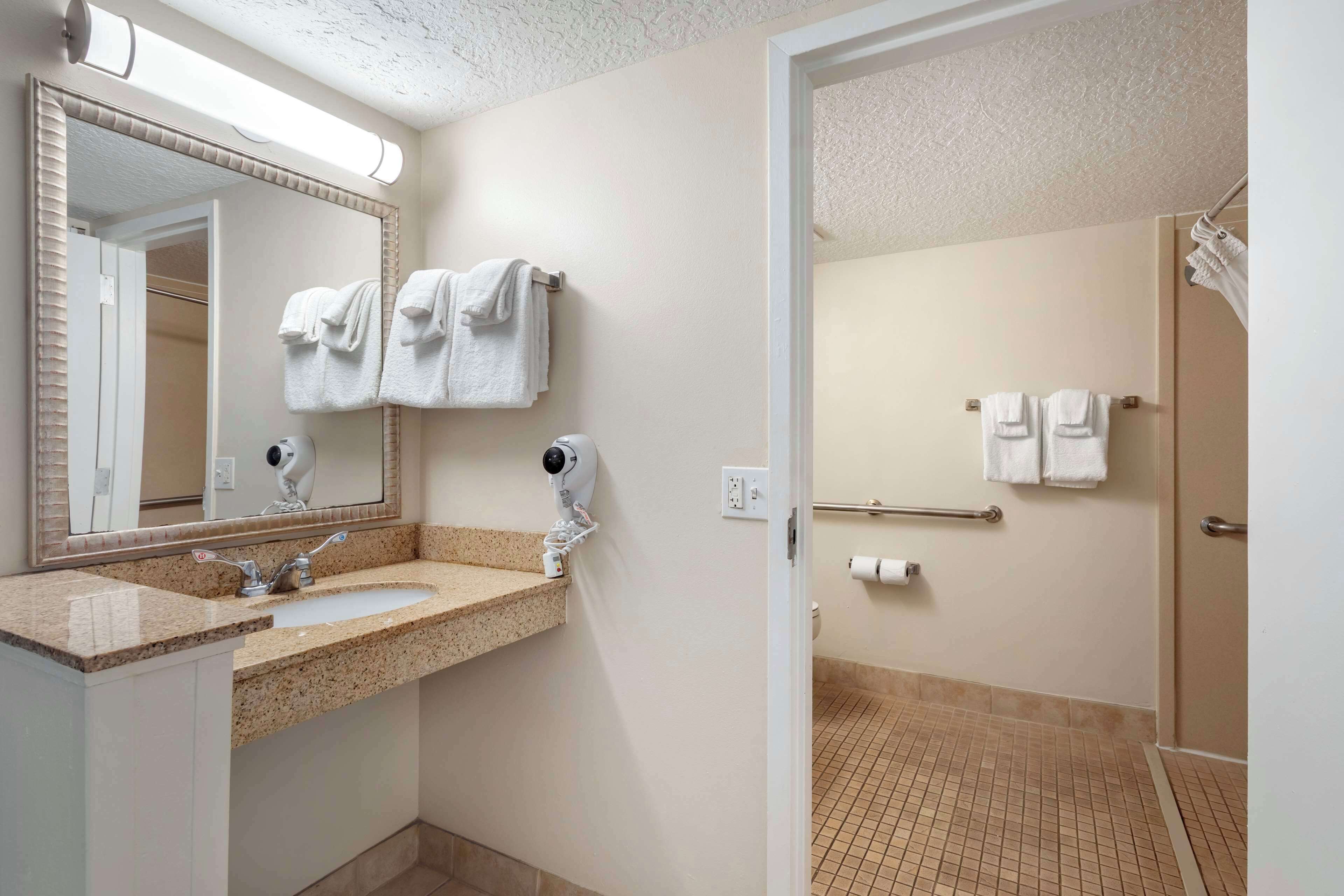 Une salle de bain équipée d’un lavabo, d’un miroir, d’un porte-serviettes et d’un espace douche.