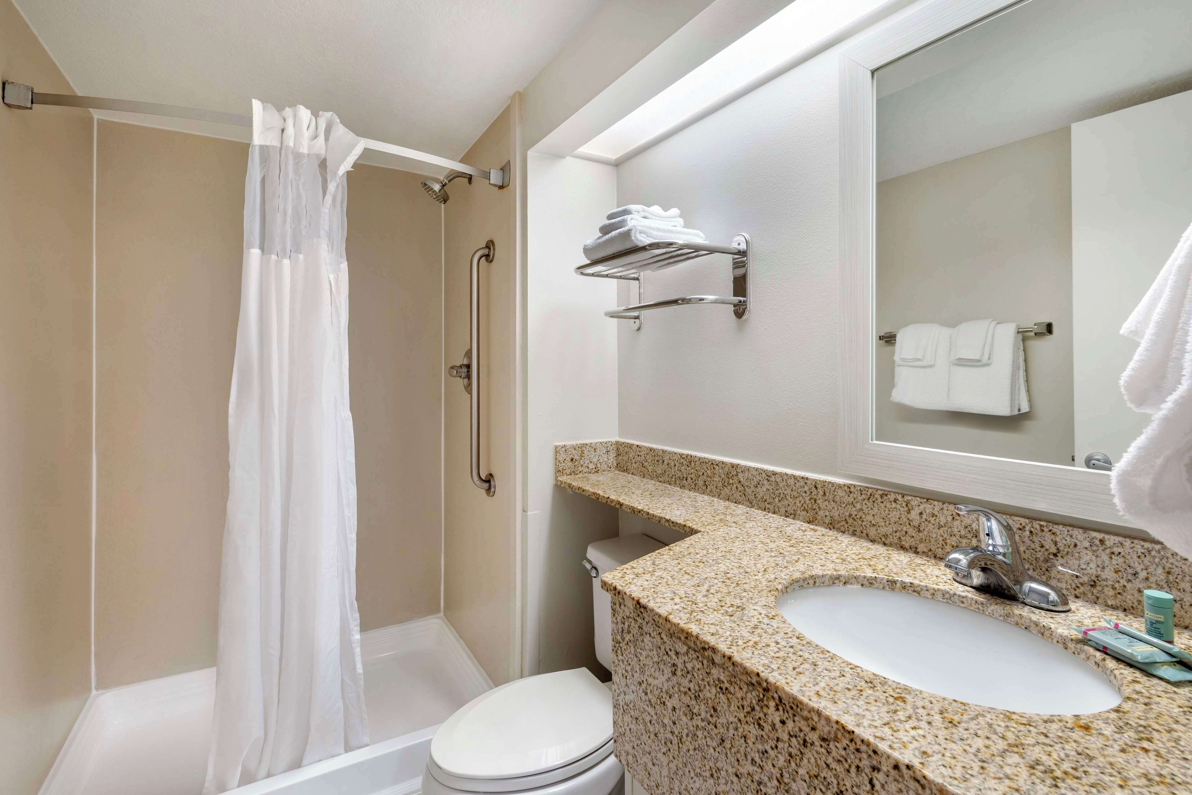 A bathroom with a shower, toilet, sink, and towel rack.
