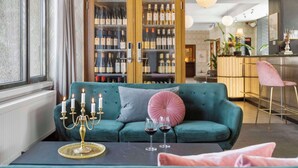 A cozy living area with a teal sofa, a candelabra, and wine glasses on a table. - Hotel Astoria, BW Signature Collection (Copenhagen)