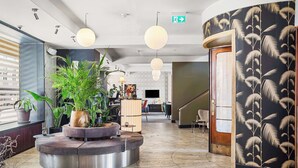 A modern lobby with a reception desk, potted plants, a staircase, and a patterned wall. - Hotel Astoria, BW Signature Collection (Copenhagen)