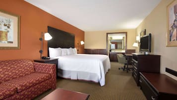 Una habitación de hotel con una cama, un escritorio, una silla, un sofá y un televisor.