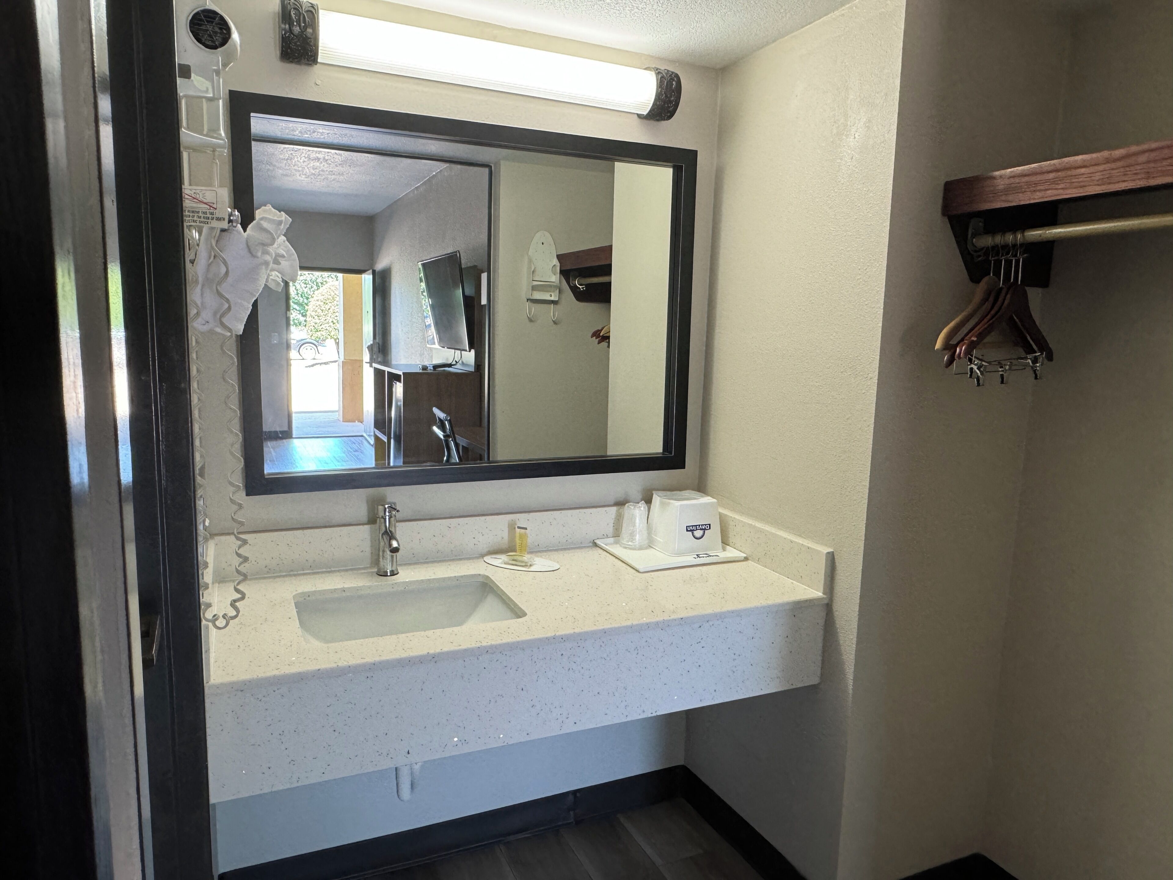 A bathroom with a large mirror, a sink, and a towel rack.