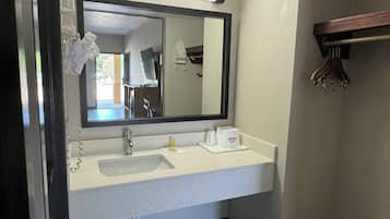 A bathroom with a large mirror, a sink, and a towel rack.