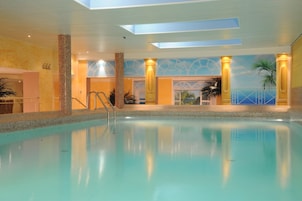 Una piscina con vista chiara del soffitto e delle pareti, inclusa una parete decorativa raffigurante una spiaggia.