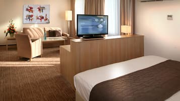 Ein Hotelzimmer mit einem Bett, einem Schreibtisch mit Fernseher, einer Couch und einem Sessel.