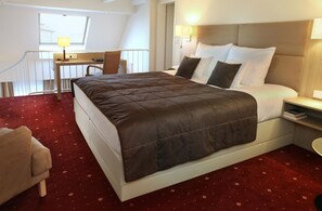 Une chambre d’hôtel avec un grand lit, un bureau et une chaise.