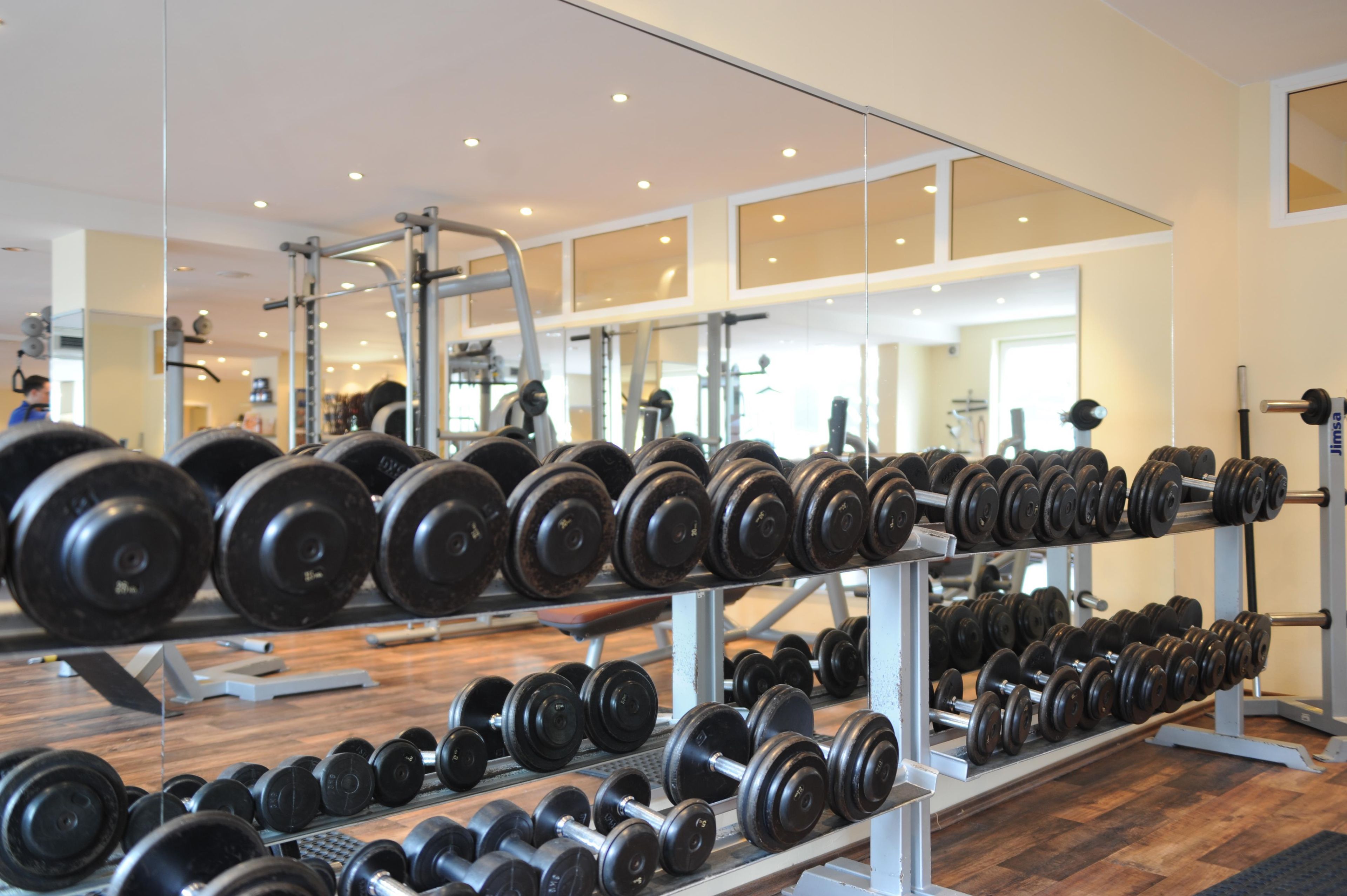 Uma academia com fileiras de halteres e aparelhos de musculação.