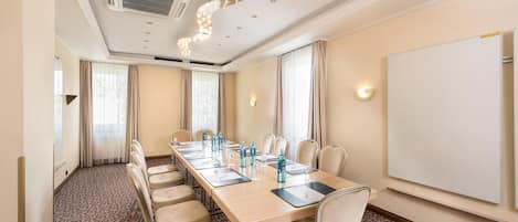 A conference room with a long table, chairs, a whiteboard, and a patterned carpet.
