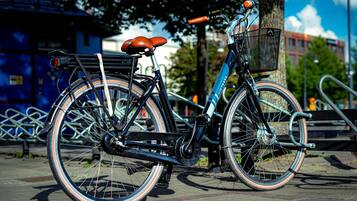 A bicycle parked on a paved surface with a basket and a seat.