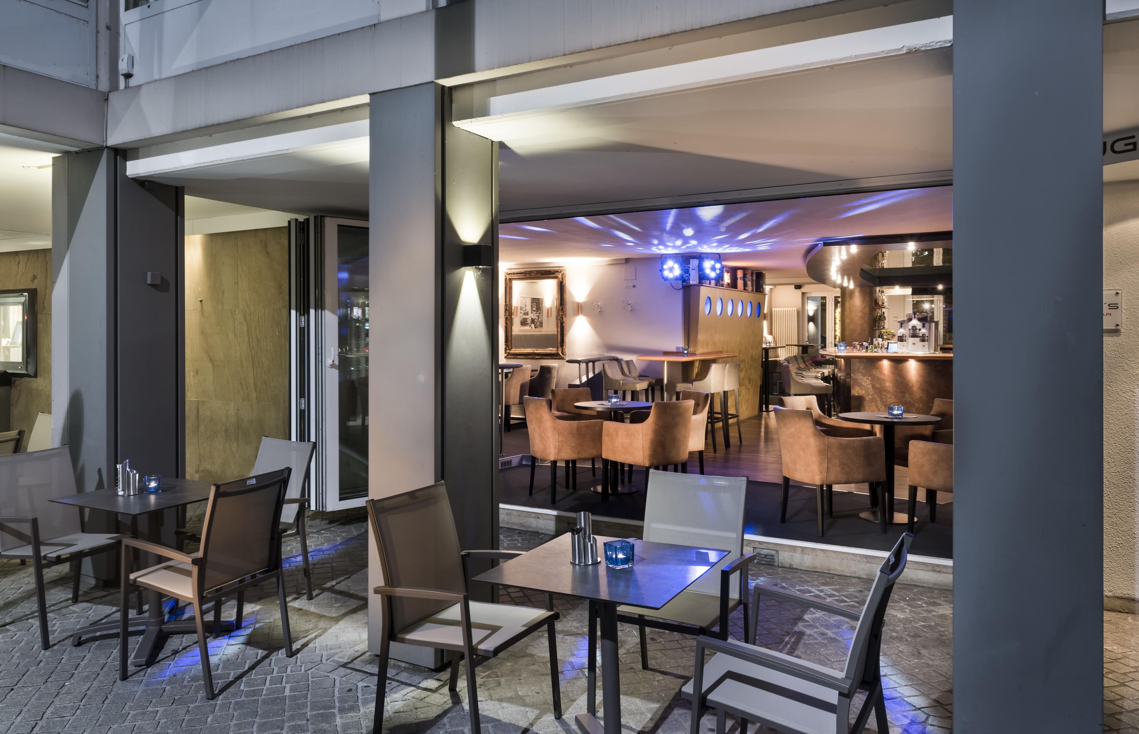 Ein moderner Innenbereich mit Essbereich, Tischen und Stühlen, einer Bar mit Theke und einem großen Spiegel an der Wand.