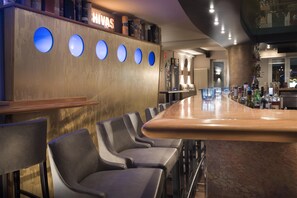 A bar area with a long counter, multiple stools, and a wall with circular light fixtures. - Best Western Hotel Zur Post (Bremen)