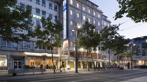 Un hôtel à plusieurs étages, avec une entrée bien visible et un vélo garé à l’extérieur.