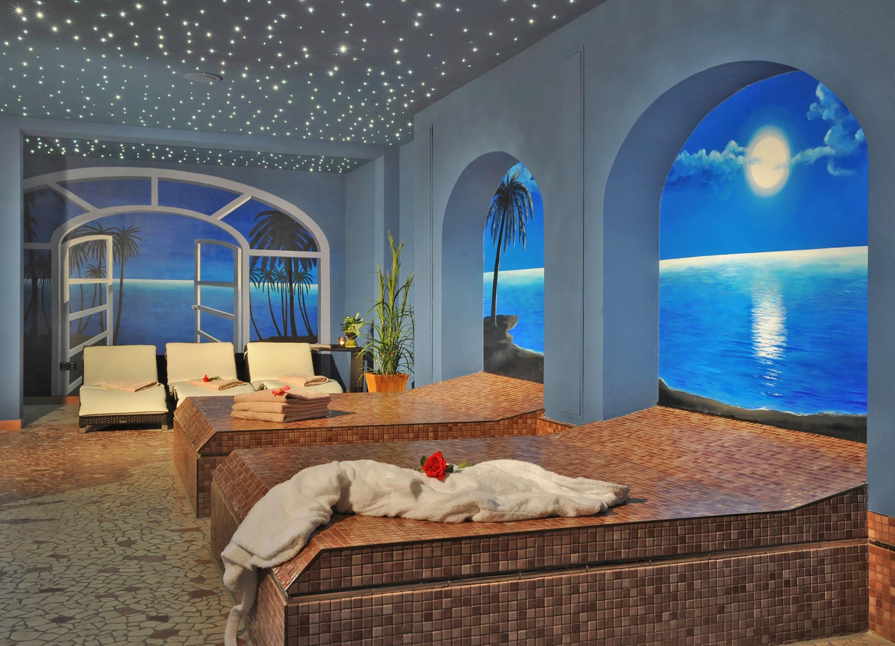 Ein Zimmer mit einem Bett, zwei Stühlen, einem kleinen Tisch und einem großen Fenster mit Meerblick.