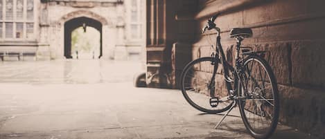 A bicycle parked against a building facade with an arched entrance.