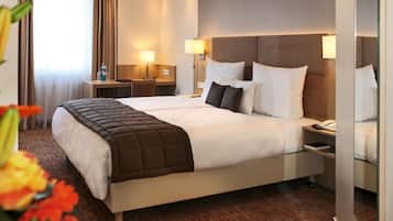 Ein Hotelzimmer mit einem Doppelbett, Nachttischen, Lampen, einem Schreibtisch und einem Stuhl.
