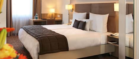 Camera d'albergo con un letto matrimoniale, comodini, lampade, una scrivania e una sedia.