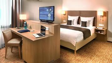 Ein Hotelzimmer mit Schreibtisch, Bett, Fernseher und Telefon.