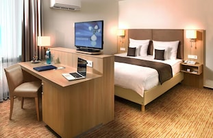Una habitación de hotel con escritorio, cama, televisor y teléfono.