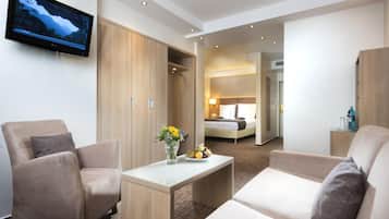 A hotel room with a TV, a desk with a vase of flowers, and a bed with a nightstand.