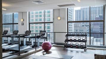 A gym with treadmills, a stationary bike, a pink exercise ball, and a rack of kettlebells.