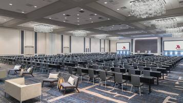 A large conference room with rows of chairs, a stage, and a Marriott logo on the screen.