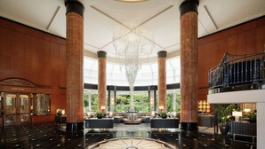 A spacious lobby with high ceilings, large chandeliers, and a central seating area.