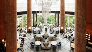 A spacious lobby with high ceilings, large marble columns, and a central chandelier. Tables and chairs are arranged in a circular pattern around a central seating area. - The Westin Tokyo (Tokyo)