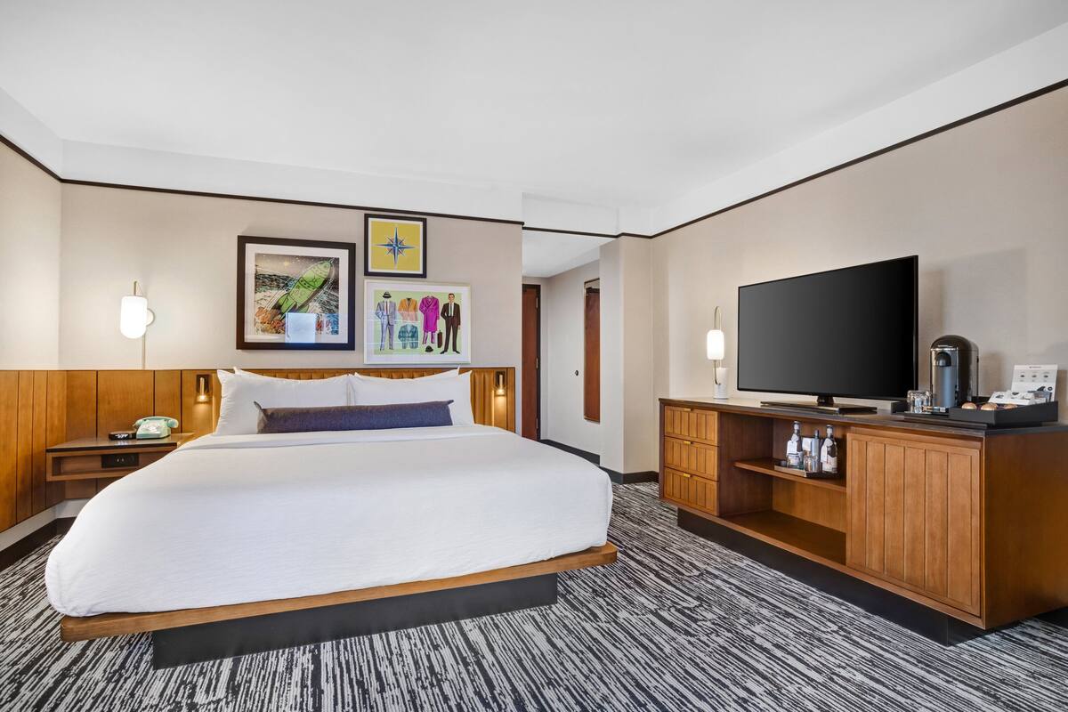 Ein Hotelzimmer mit einem großen Bett, einem Flachbildfernseher, Holzmöbeln und Bildern an den Wänden.