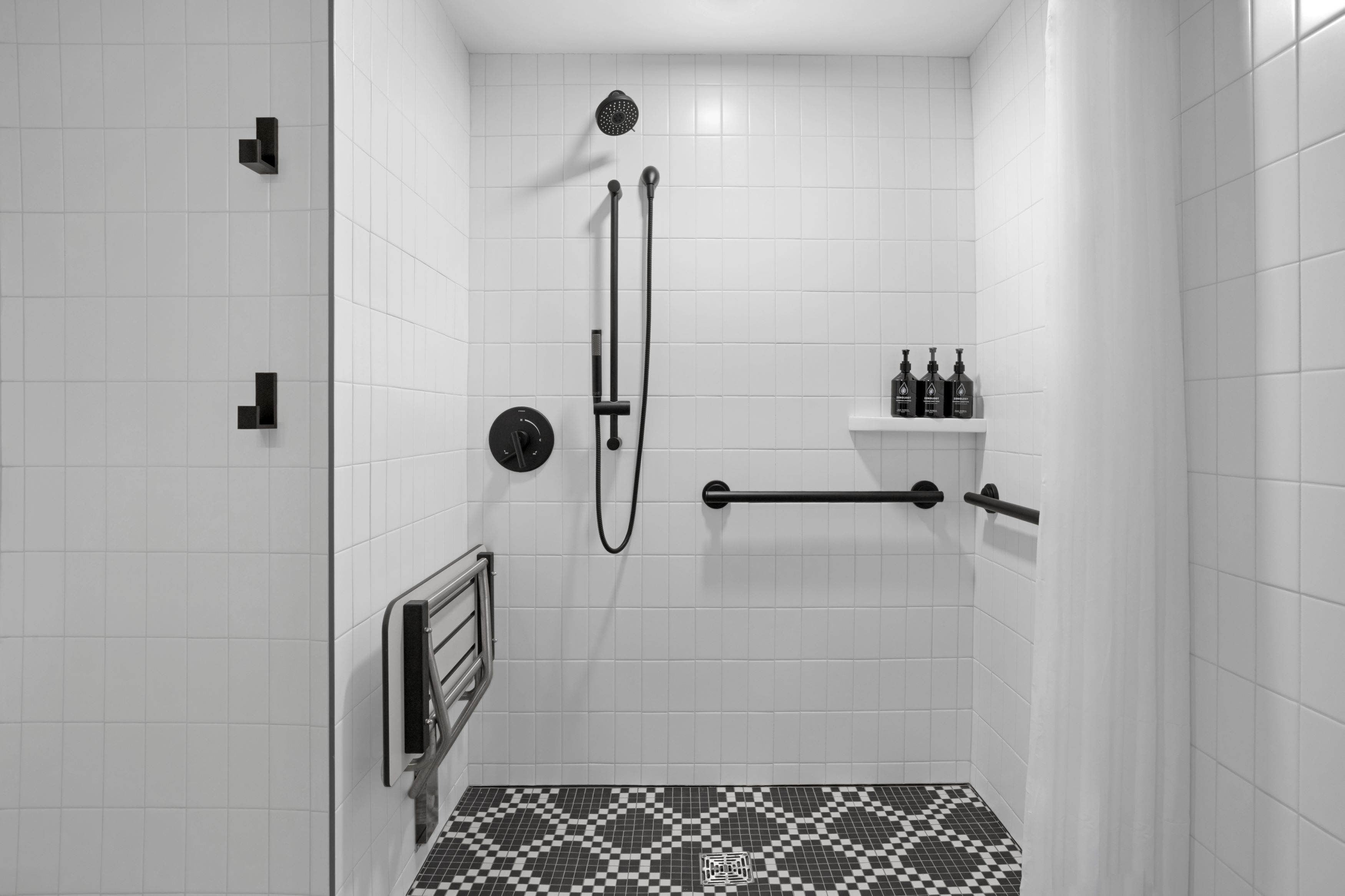 Een moderne douche ruimte met witte betegelde wanden, een zwart-wit schaakkleurend vloertje en een plank met toiletartikelen.