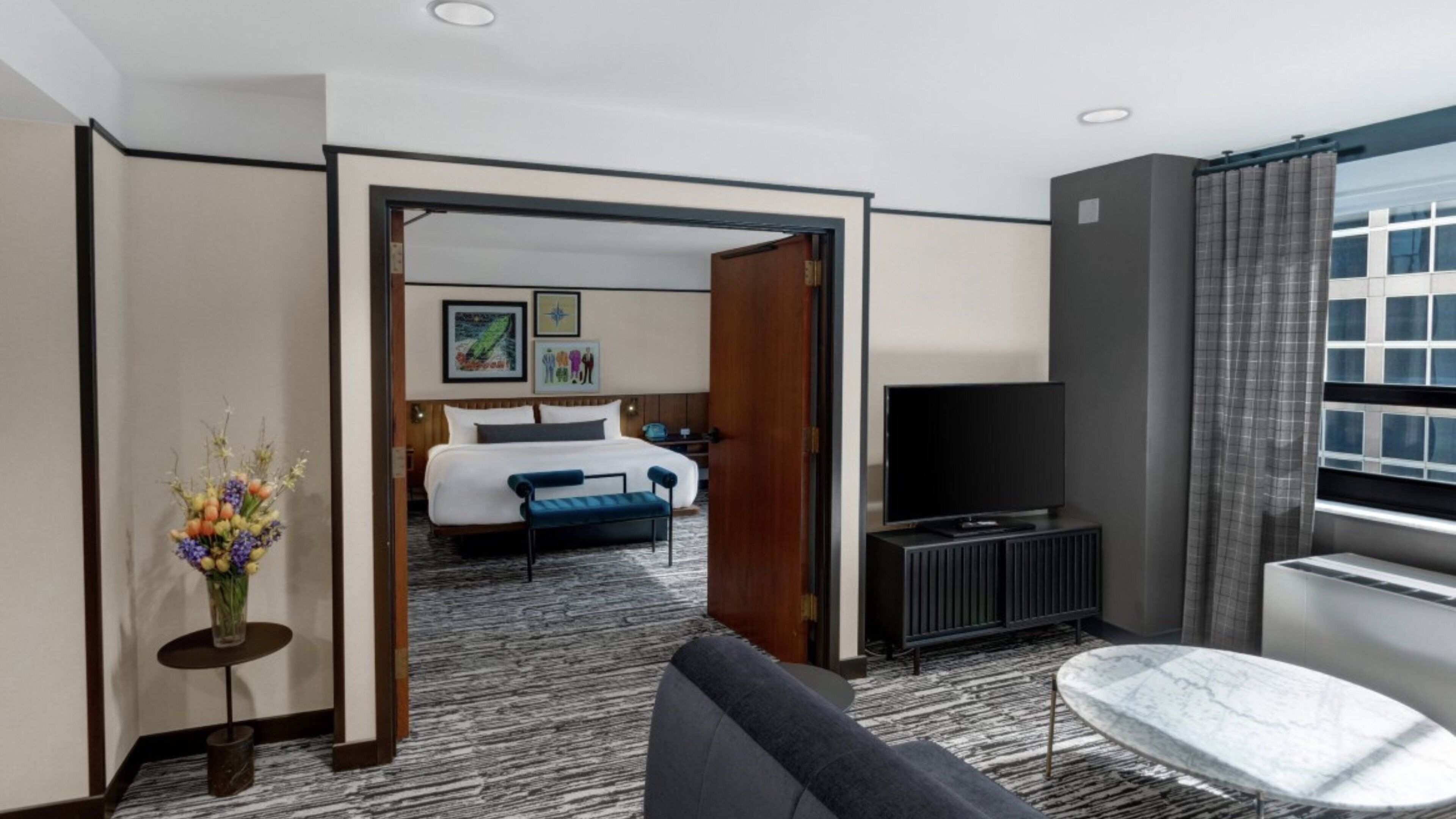 A hotel room with a bed, a TV, a sofa, and a coffee table.
