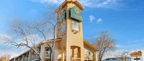 Un La Quinta Inn con una torre destacada, varios balcones y una vista despejada del entorno.
