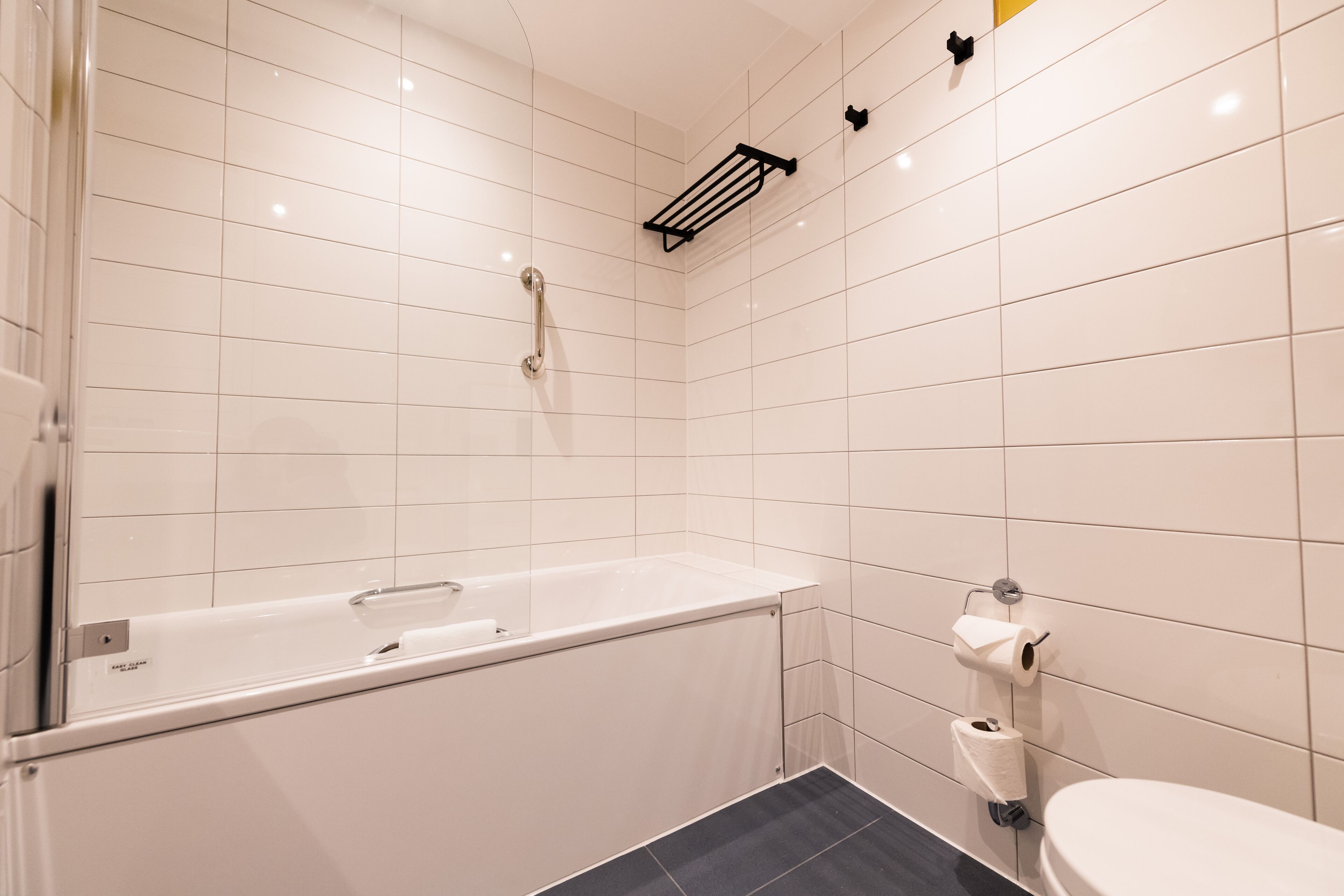 Un baño moderno con una bañera blanca, un inodoro y un perchero para toallas.