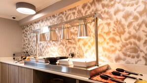 Une cuisine moderne avec un dosseret en marbre, des appareils électroménagers en acier inoxydable et des luminaires suspendus.