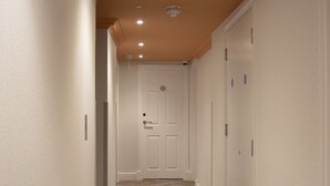 Un couloir avec un tapis à motifs, des murs blancs et des portes donnant sur différentes pièces.