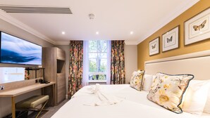 Une chambre d’hôtel avec un lit, un bureau, une télévision et une fenêtre avec des rideaux.