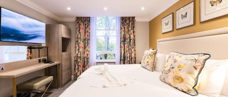 Une chambre d’hôtel avec un lit, une télévision, un bureau et une fenêtre avec des rideaux.