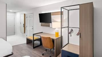 A modern bedroom with a desk, chair, bed, wardrobe, and TV.
