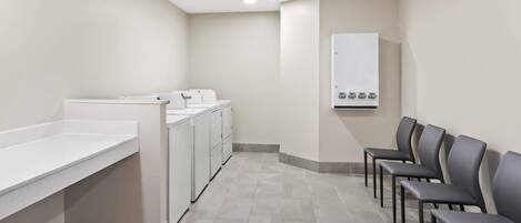 Un área de lavandería con lavadora, secadora y un panel de servicios que incluye un termostato.