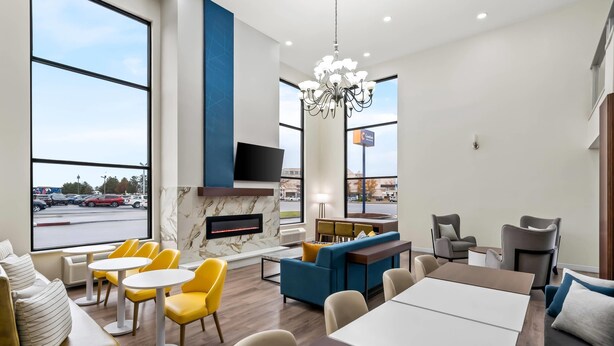 A modern hotel lobby with a seating area, a fireplace, and a large window overlooking a parking lot. - Comfort Inn & Suites Salt Lake City I-80 I-15 Downtown (Salt Lake City)