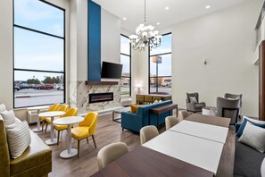 A modern hotel lobby with a seating area, a fireplace, and a large window overlooking a parking lot. - Comfort Inn & Suites Salt Lake City I-80 I-15 Downtown (Salt Lake City)