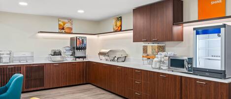 A modern kitchen with wooden cabinets, a microwave, a coffee machine, and a refrigerator.