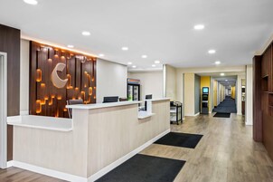 Una zona de recepción con un panel de madera, un mostrador de recepción y un pasillo que conduce a otras habitaciones.