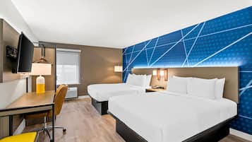 A hotel room with two beds, a desk with a chair, a TV, and a window.