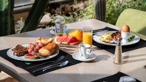 A breakfast table with croissants, fruit, eggs, and juice.