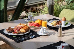 A breakfast table with croissants, fruit, eggs, and juice.