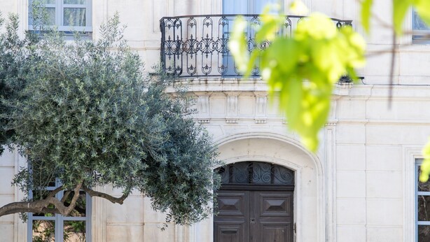 A building with a stone facade, a dark wooden door, and a wrought iron staircase leading to a balcony. - Mercure Arles Centre Arenes (Arles)