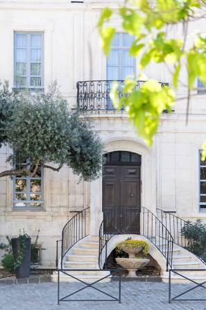 A building with a stone facade, a dark wooden door, and a wrought iron staircase leading to a balcony.