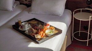 A neatly made breakfast tray with croissants, pastries, and beverages on a bed in a hotel room.